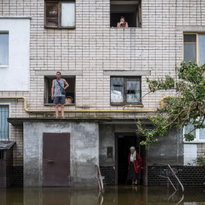 Virginie Nguyen Hoang. Ukraine, Kherson city, 10/06/2023 : des habitants du quartier de Korabel guettent l’arrivée des services d’urgence pour faire évacuer la vieille dame au seuil de sa porte. Suite à la destruction du barrage de Kakhovka, tout le quartier sud de Kherson a été complètement inondé par le fleuve Dniepr ayant monté de 5 mètres. © Virginie Nguyen Hoang / Collectif HUMA